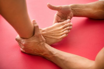 Osteopath assessing a hallux valgus or bone growth at the base of the big toe on a woman patient in a close up on her foot